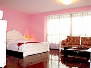 1 dormitorio con paredes rosas, 1 cama y 1 sofá en Beijing Futon Family Apartment, en Beijing