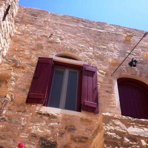 a window with purple shutters on a stone building at Patrika Traditional House in Patriká