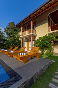 a row of wooden benches in front of a house at Villa Bentota B24 in Bentota