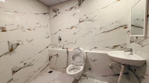 a white bathroom with a toilet and a sink at Sun Stayz Inn T - Nagar Chennai in Chennai +17 photos