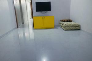 a room with a yellow cabinet with a television on the wall at Sukhada Nivas Bunglow in Trimbak