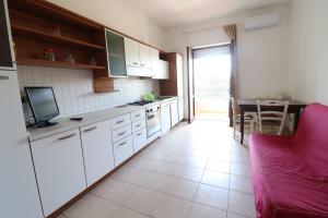 a kitchen with white cabinets and a red couch at Casa Federica Otranto Near Beach & Center AC, WiFi & 6 Sleeps in Otranto +17 photos