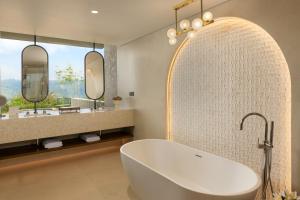 a bathroom with a white tub and two mirrors at Uga Ghiri - Ella - All Inclusive in Ella