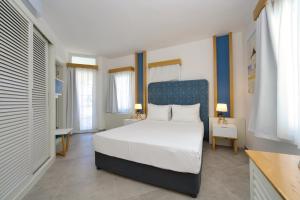 a bedroom with a white bed and a blue headboard at Labranda TMT Bodrum in Bodrum City