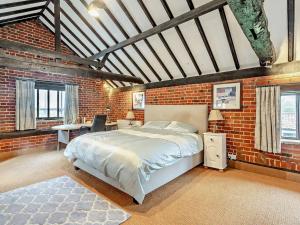 a bedroom with a bed and a brick wall at The Farmhouse - Uk48228 in Tibenham
