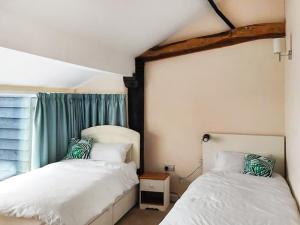 a bedroom with two beds next to a window at The Farmhouse - Uk48228 in Tibenham +10 photos