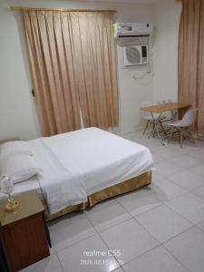 a bedroom with a bed and a table and a table at جمانا سويتس للشقق المخدومه in Al Qunfudhah