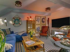 a living room with a blue couch and a tv at The Salt Loft in Fowey
