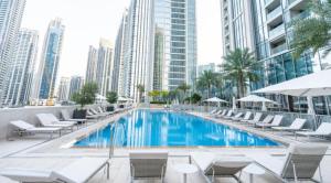 a swimming pool with chairs and a building at Exquisite 2BDR Retreat In Forte-33 in Dubai