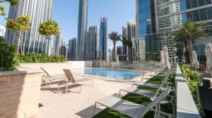 a swimming pool with chairs and a city skyline at Exquisite 2BDR Retreat In Forte-33 in Dubai