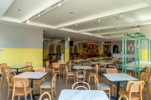 a dining room with tables and chairs and yellow walls at Amaris Hotel Gorontalo in Gorontalo