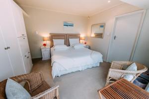 a bedroom with a bed and two chairs and a table at Dolphins' Playground Beachfront B&B in Plettenberg Bay