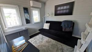 a living room with a black couch in a tiny house at Nalle's in Stavtrup
