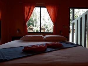 a bedroom with a large bed with red walls and a window at Green Chilli Bungalows in Ko Lanta