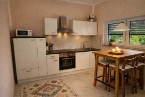 a kitchen with white cabinets and a wooden table at Apartment im schönen Taunus in Dickschied +6 photos