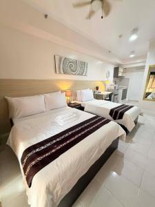 two beds in a large room with a kitchen at Cozy Studio Condo with Stunning Tagaytay Views in Tagaytay