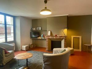 a living room with a fireplace and a table and chairs at Les Gites Saint Aignan - Proche du Zoo de Beauval in Saint-Aignan