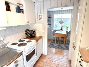 a kitchen with a stove and a dining room with a table at Wonderful cottage close to lakes in Södra Rörum
