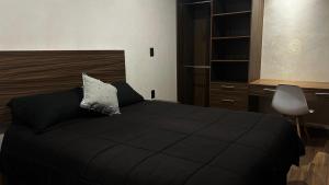 a bedroom with a black bed with a pillow on it at Suites Oros in Oaxaca City