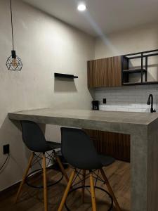 a kitchen with a large counter and two chairs at Suites Oros in Oaxaca City +34 photos