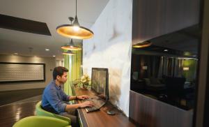 a man sitting at a desk using a laptop computer at Bonnet Hotel Surabaya in Surabaya