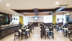 a restaurant with tables and chairs and a bar at Bonnet Hotel Surabaya in Surabaya