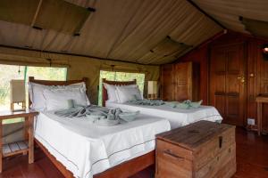 two beds in a room with white sheets at Kelora Bush Camp in Hoedspruit