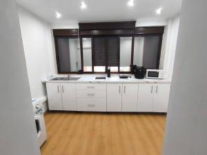 a kitchen with white cabinets and a large window at Soluna Alcala in Alcalá del Río
