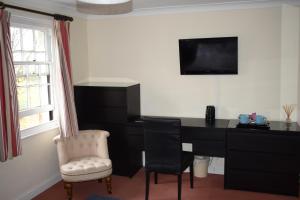 um quarto com uma secretária, uma televisão e uma cadeira em The Swan at Great Kimble em Aylesbury