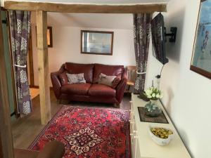 a living room with a leather couch and a rug at fairfeilds cottage Frog Trotters Bottom in Hartpury