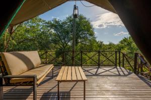 a porch with a couch and a table on a deck at Kelora Bush Camp in Hoedspruit