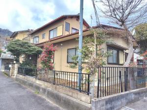 a house with a fence next to a street at OZigaoka Guest House in Otsu