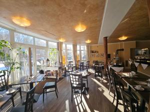 a dining room with tables and chairs and windows at Hotel Garni Auszeit in Boltenhagen
