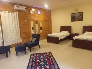 a hotel room with two beds and a chair and a rug at Gahirat Castle Chitral in Chitral