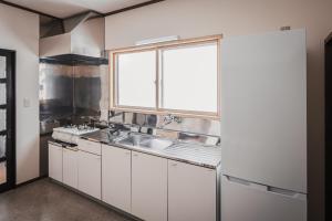 a kitchen with white cabinets and a sink and a window at Villa Mimosa Myoko in Myoko +13 photos
