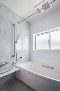 a white bathroom with a tub and a shower at Villa Mimosa Myoko in Myoko