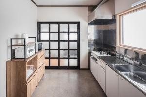 a kitchen with white cabinets and a sink and a window at Villa Mimosa Myoko in Myoko