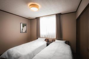 two beds in a room with a window at Villa Mimosa Myoko in Myoko