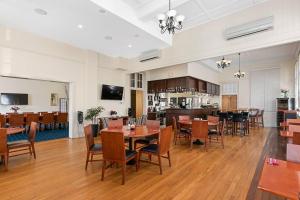 a dining room with tables and chairs and a kitchen at Quality Hotel Regent Rockhampton in Rockhampton