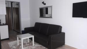 a living room with a black couch and a table at Apartament 22 nad morzem in Świnoujście