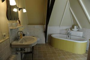 een badkamer met een wastafel en een bad naast een wastafel bij Moushouk Bed and Breakfast in Oostwold