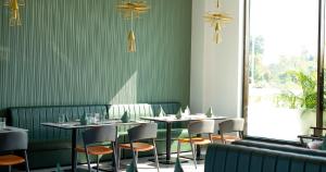 a restaurant with tables and chairs in a room with green walls at Aurum by R J Resorts in Siliguri