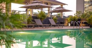 a pool with chairs and umbrellas next to a building at Aurum by R J Resorts in Siliguri