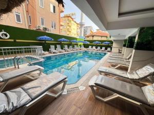 a large swimming pool with lounge chairs and umbrellas at Aslan City Hotel - Ex Beste Hotel in Alanya