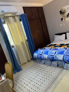 a bedroom with a bed and a window with blue curtains at Résidence Ephrata in Cocody