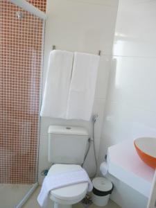 Baño con aseo y toallas colgando encima. en Flat no Farol, en Salvador