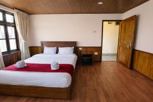 a bedroom with a large bed with a red blanket at Hotel Tashiling Stay in Pelling