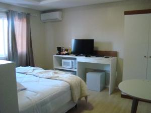 a bedroom with a bed and a desk with a television at Apartamentos Pórtico II in Gramado