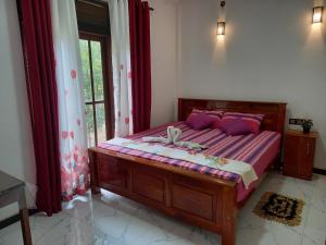 a bedroom with a bed with purple pillows and a window at Silent Peacock Villa And Restaurant in Tangalle