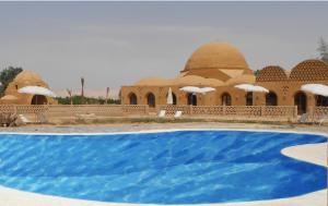a building with a blue pool in front of it at Shanda Lodge Desert Resort in Al Qaşr